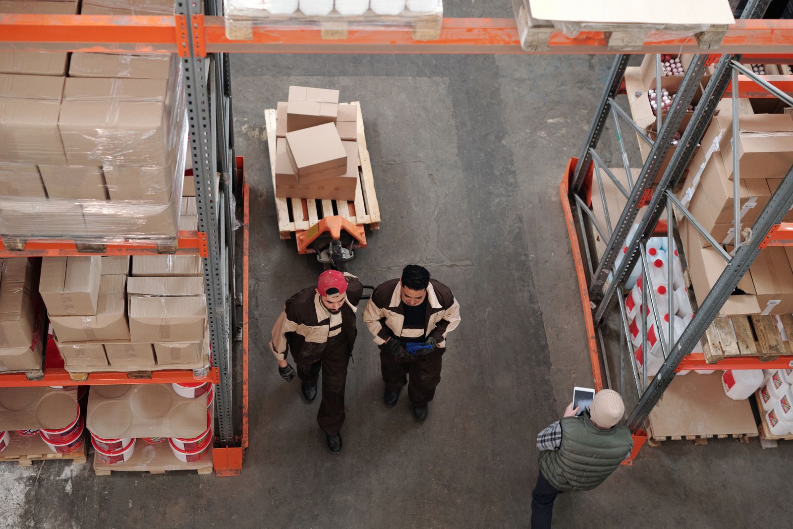 Warehouse team coordinating beside pallets and boxed goods